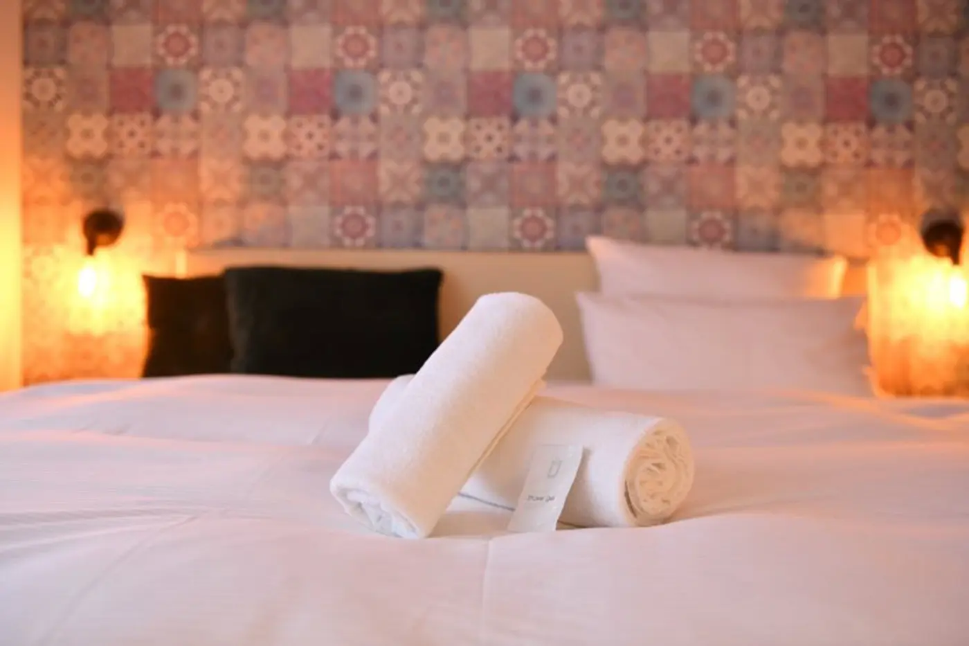 Bett im Hotelzimmer mit schön aufgerollten Handtüchern